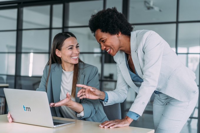 two office workers viewing content on a laptop