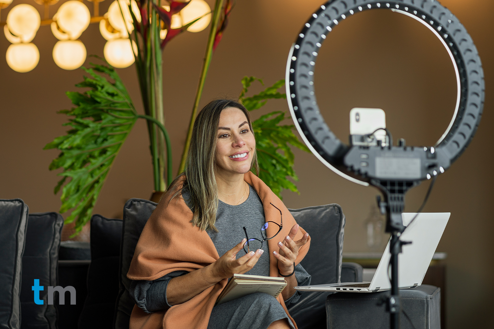 Woman performing a live broadcast from home while using her ring of light to illuminate herself and her cell phone to make the video